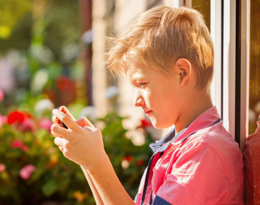 Photograph of a boy looking at a phone in a garden